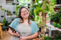 Frau mit Down-Syndrom arbeitet in einem Blumenladen mit Tablet