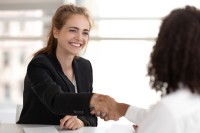 Zwei Frauen geben sich nach einem erfolgreichen Bewerbungsgespräch die Hand.