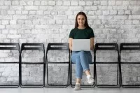 Junge Frau mit Laptop warten auf ihr Bewerbungsgespräch
