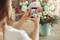 Eine Auszubildende zur Floristin fotografiert einen Blumenstrauß.