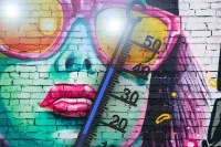 Graffiti einer jungen Frau mit Sonnenbrille und blaues Thermometer