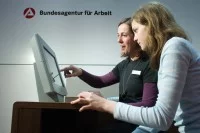Eine Fachangestellte für Arbeitsmarktdienstleistungen berät eine Jugendliche an einem Stand der Bundesagentur für Arbeit über Ausbildungsberufe.