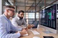 Zwei Kaufmänner für Digitalisierungsmanagement diskutieren Statistiken zu den Finanzen des Unternehmens.