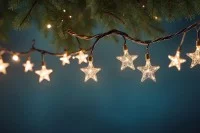 Eine leuchtende Lichtekette mit Sternen unter einem Tannenzweig auf blauem Hintergrund