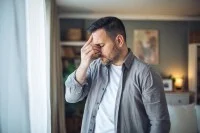 Ein Mann im Hemd fasst sich an den Kopf.