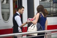 Ein Schaffner berät eine Frau vor einem Zug.