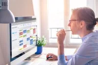 Eine Frau organisiert Termine, Aufgaben und Arbeitszeiten am Computer mit einem digitalen Kalender.
