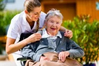 Altenpflegerin mit einer Seniorin im Rollstuhl