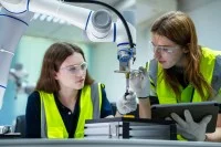 Auszubildende arbeiten an einem Roboterarm