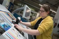 Eine Medientechnologin Druck prüft die Druckqualität mit einem Spektralphotometer.