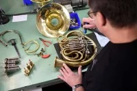 Ein Metallblasinstrumentenmacher baut in seiner Werkstatt ein Horn.