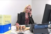 Eine Notarfachangestellte kümmert sich um die telefonische Korrespondenz mit einem Mandanten.