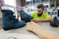 Ein Orthopädieschuhmacher prüft einen fertiggestellten orthopädischen Schuh.
