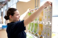 Eine Packmitteltechnologin überprüft die frisch gedruckte Verpackung für verschiedene Cremes.