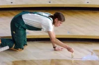 Ein Parkettleger versiegelt das Parkett im Plenarsaal des Sächsischen Landtags in Dresden.