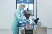 Eine Pharmakantin arbeitet in einem Pharmazieunternehmen an der Produktion von Tabletten.