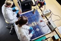 Zwei Physiklaboranten arbeiten an einem 3D-gedrucktem Turbinenrad und an einem Solarpanel.