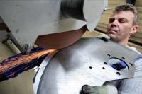 Ein Präzisionswerkzeugmechaniker der Firma Astor Schneidwerkzeuge GmbH schleift ein Industriemesser aus rostbeständigem Spezialstahl.