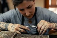 Eine Silberschmiedin fertigt in ihrer Werkstatt eine Kette an.
