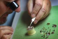Ein Uhrmacher arbeitet mit einer Pinzette an einer mechanischen Armbanduhr. 