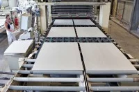 Ein Verfahrensmechaniker in der Steine- und Erdenindustrie überwacht die Produktion von Gipsfaserplatten.