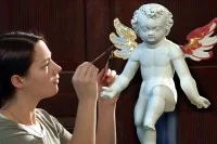 Eine Vergolderin belegt die Flügel einer Engelfigur aus dem 17. Jahrhundert mit 24-karätigem Blattgold. 