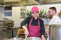 Eine Fachkraft Küche unterstützt den Koch eines Wirtshauses bei der Zubereitung der wohlschmeckenden Speisen.