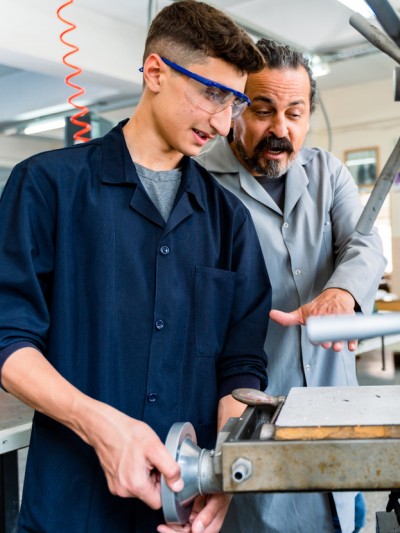 Ein Azubi arbeitet unter Anleitung an einer Maschine