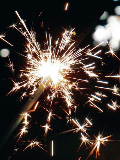 Eine gezündete Wunderkerze auf dunklem Hintergrund mit Reflektion.