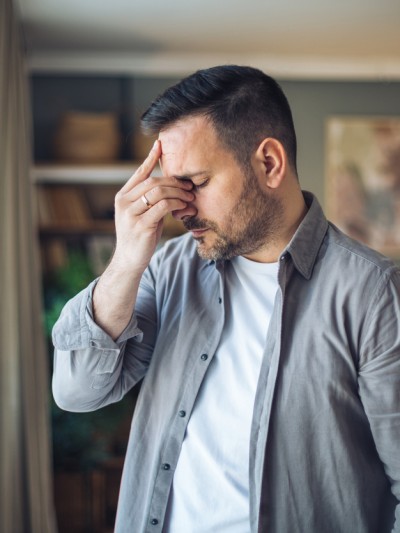 Ein Mann im Hemd fasst sich an den Kopf.