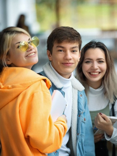 Fünf Schülerinnen und Schüler von ungefähr 17 Jahren stehen im Halbkreis und lachen in die Kamera.
