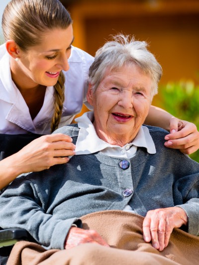 Altenpflegerin mit einer Seniorin im Rollstuhl
