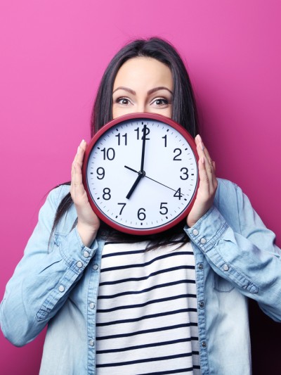 Eine Frau hält eine große runde Uhr vor sich.