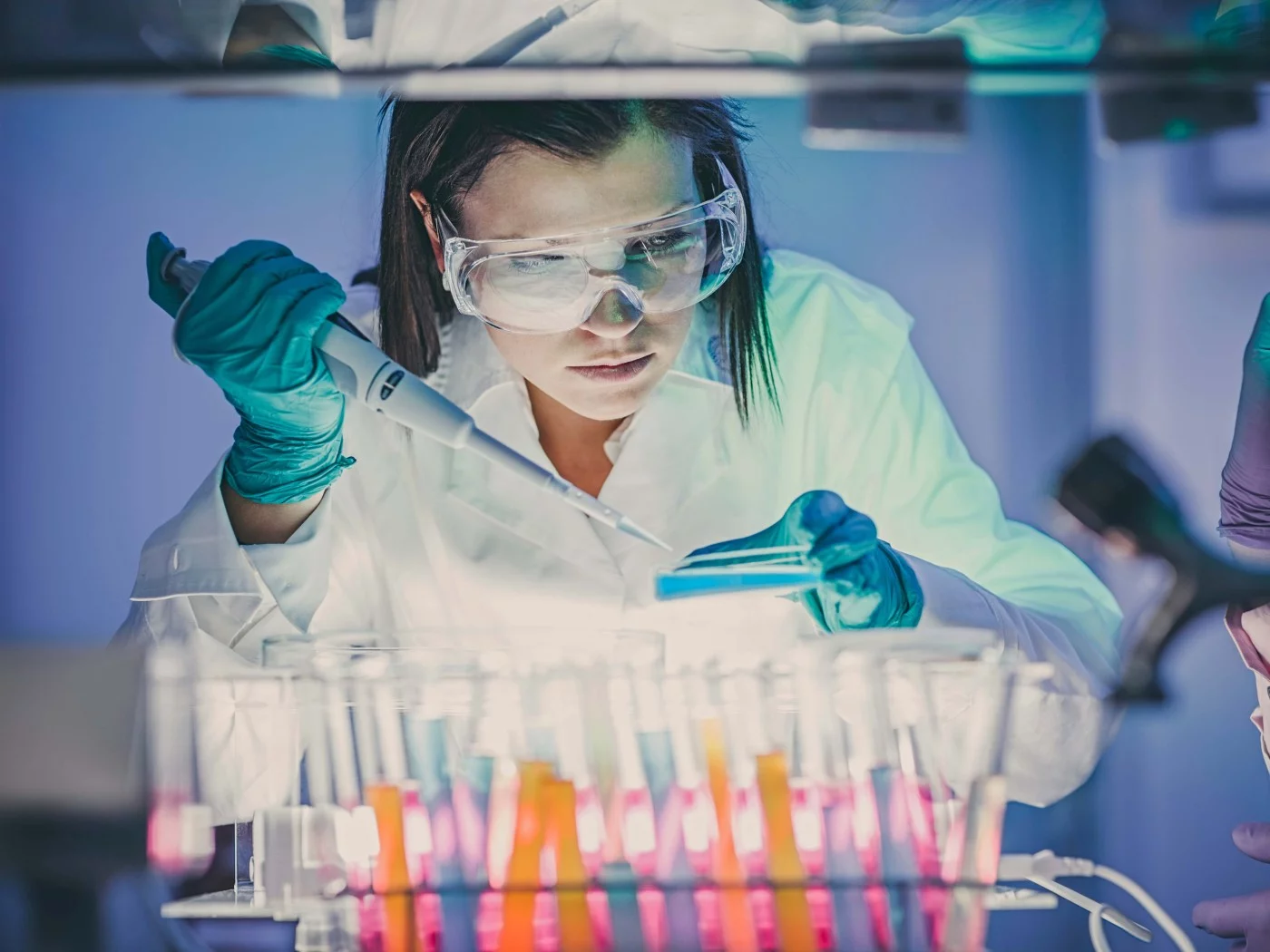 Eine Chemielaborantin gibt mit einer Pipette eine Substanz zu einer Lösung hinzu.