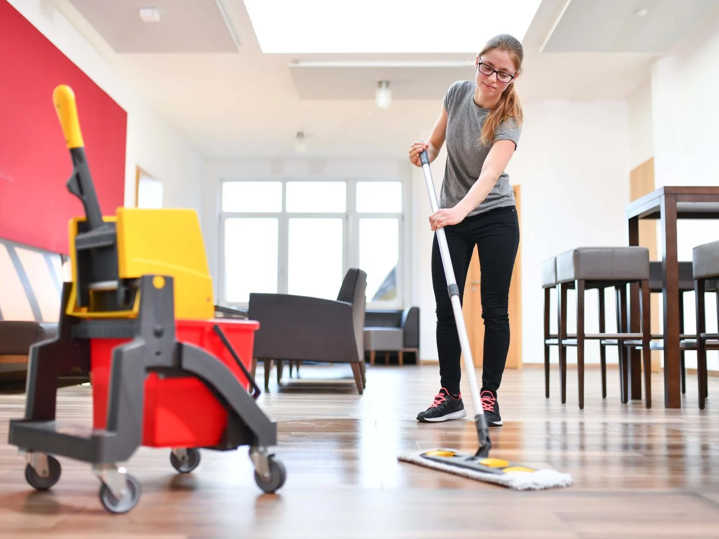 Eine Hauswirtschafterin wischt in einem Freizeitzentrum den Fußboden.