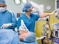 Eine Patientin in einem Krankenhaushemd wird während der Operation von einer anästhesietechnischen Assistentin betreut.