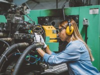 Eine Anlagemechanikerin überprüft eine CNC-Maschine, die Werkstücke mit hoher Präzision automatisch herstellt.