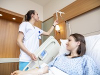Eine Gesundheits- und Krankenpflegerin überprüft die Einstellung des Tropfes einer Patientin. 