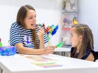 Eine Logopädin übt mit einem Vorschulkind die korrekte Aussprache von Silben.