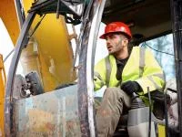 Ein Baugeräteführer fährt einen Bagger auf einer Baustelle.