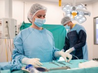 Eine operationstechnische Assistentin in OP-Kleidung richtet Instrumente auf einem Tisch für eine bevorstehende Operation her.