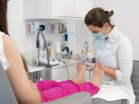 Eine Podologin behandelt die Füße einer Patientin in einer Praxis.