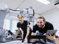 Eine technische Assistentin testet mit einem Techniker in einem Labor den Prototyp eines neuen Roboters.