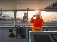 Ein Binnenschiffer hält auf der Brücke des Schiffs Ausschau in Richtung Hafen.
