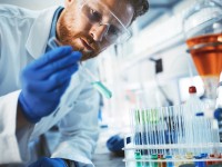 Ein chemisch-technischer Assistent untersucht im Labor eine Probe mit verschiedenen chemischen Reagenzien.