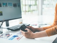 Ein Fotodesigner gleicht die erstellten Bilder auf seiner Kamera mit denen am Computer ab.