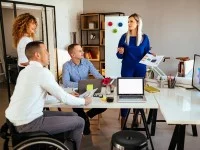 Eine Gruppe von vier Menschen versammeln sich um einen Tisch und besprechen eine Werbekampagne. 