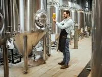 Ein Brauer prüft ein frisch aus der Brauereianlage gezapftes Bier.
