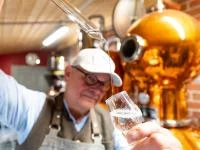 Ein Brenner kontrolliert in seiner Brennerei den von ihm gebrannten Gin.