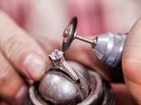 Nahaufnahme von einem Diamantring, der mit einer Polierscheibe, die auf einem Dremel steckt, poliert wird.